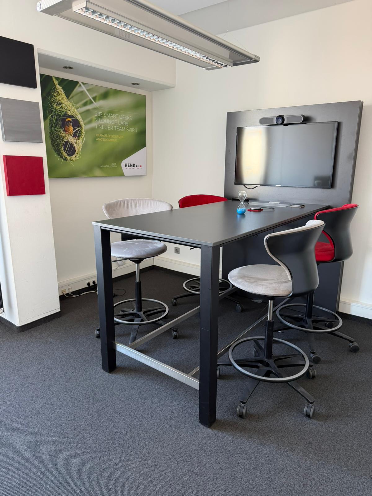 Moderner Thinktank mit Steh-Meeting-Tisch, Hockern und Monitor-Setup