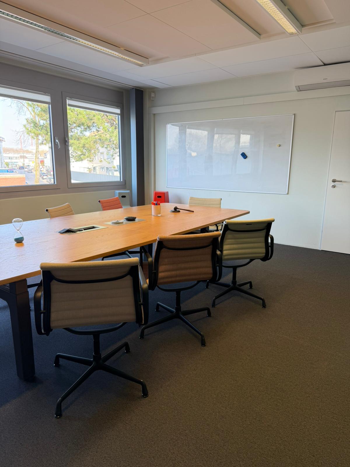 Der große, klimatisierte Executive Meeting Space mit einem höhenverstellbaren Holztisch, ergonomischen Design-Stühlen und einem Whiteboard für Strategietage