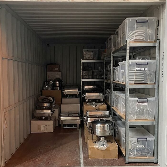 Gewerblich genutzter Lagercontainer mit Regalen voller Transportboxen, Veranstaltungstechnik und Equipment